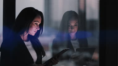 Businesswoman and reflection working late using digital tablet with bokeh effect