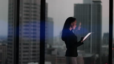 Businesswoman and reflection working late using digital tablet with bokeh effect