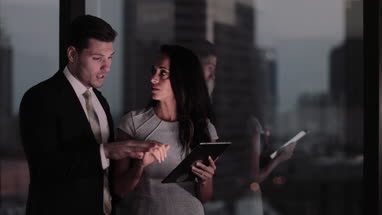 Businesswoman and businessman working late using digital tablet