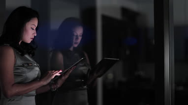 Businesswoman and reflection working late using digital tablet