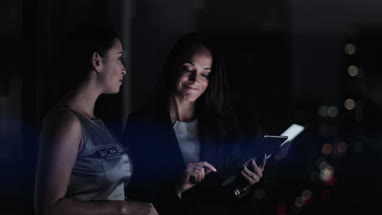 Businesswomen working late using digital tablet