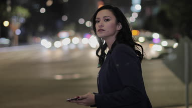 Young adult female using smartphone outdoors at night