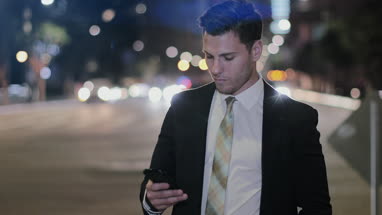 Businessman using smartphone outdoors at night