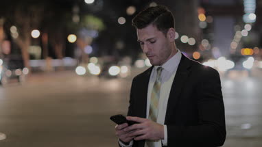 Businessman using smartphone outdoors at night