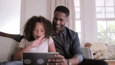 African American father and daughter using digital tablet for a videocall