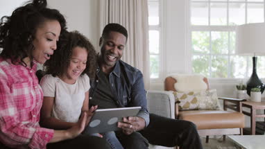 African American family watching video on digital tablet at home