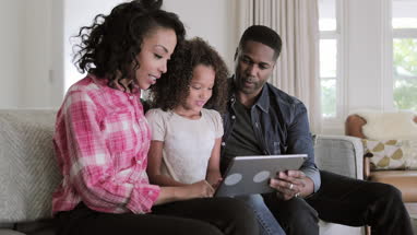 African American family watching video on digital tablet at home