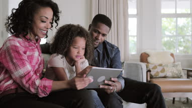 African American family watching video on digital tablet at home