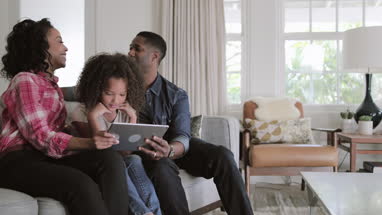 African American family watching video on digital tablet at home