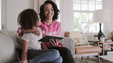 African American mother and daughter watching entertainment on digital tablet at home