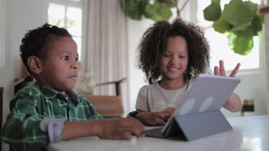 African American brother and sister playing together on digital tablet