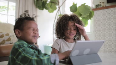 African American brother and sister playing together on digital tablet