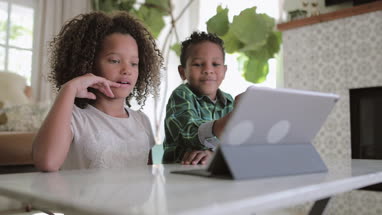 African American brother and sister playing together on digital tablet