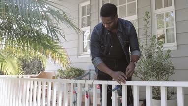 African American father hanging christmas lights outdoors