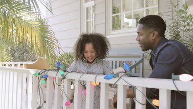 African American father and daughter turning on christmas lights outdoors