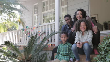 Portrait of African American family sitting outside home