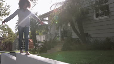 African American girl walking carefully along a wall balancing