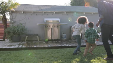 African American family playing football in yard
