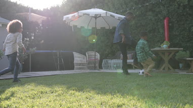 African American family playing football in yard
