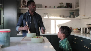 African American boy helping father prepare healthy meal in kitchen