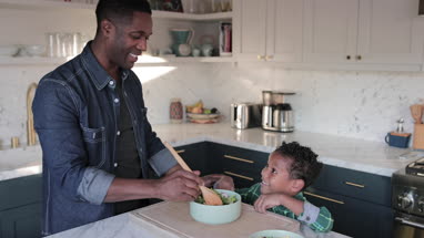 African American boy helping father prepare healthy meal in kitchen