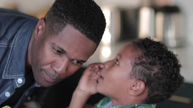 African American boy whispering in fathers ear