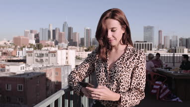 Young adult female messaging friend from a rooftop party