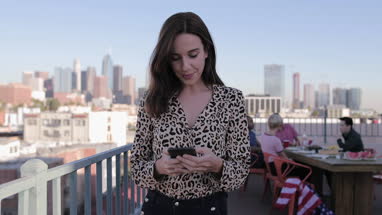 Young adult female messaging friend from a rooftop party