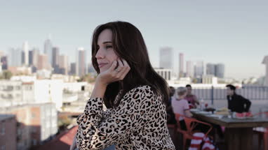 Young adult female looking out across city at a rooftop party