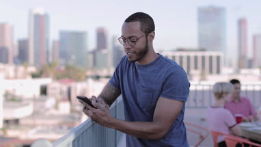 Young adult male messaging friend from a rooftop party