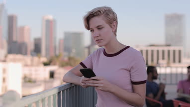 Young adult female using a smartphone at a rooftop party