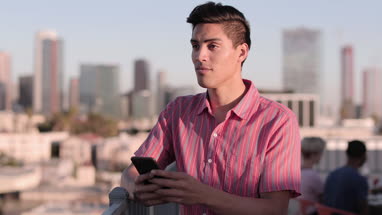 Young adult male messaging friend from a rooftop party