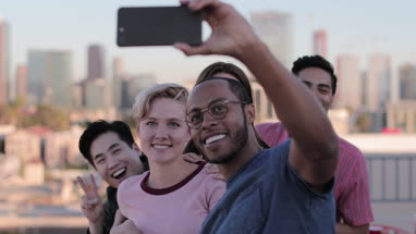 Group of friends taking selfie with city skyline in background