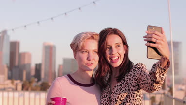 Female friends taking selfie with city skyline in background