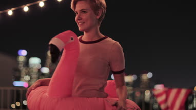 Young adult female dancing in a pool inflatable at a rooftop party