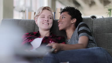 Female couple relaxing on sofa watching home entertainment