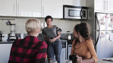 Young adult friends having coffee together in loft apartment