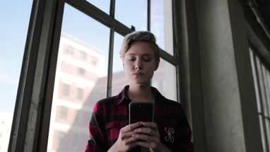 Portrait young female in loft apartment holding smartphone