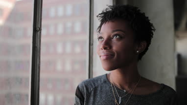 Young african american female looking out of window in loft apartment thinking