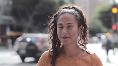 Portrait of hispanic young adult female on busy city street